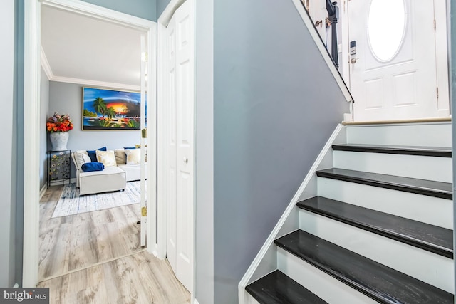 stairs with wood finished floors and crown molding