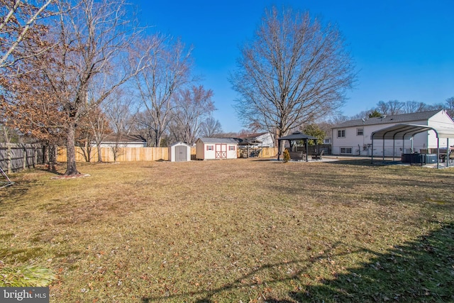 view of yard featuring a fenced backyard, an outbuilding, a gazebo, a shed, and a detached carport