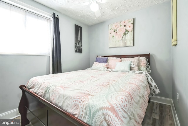 bedroom with a textured ceiling, ceiling fan, wood finished floors, and baseboards