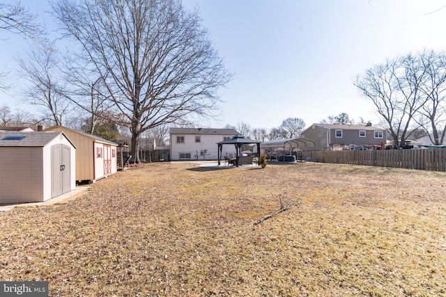 view of yard with a fenced backyard, a storage unit, an outbuilding, and a gazebo