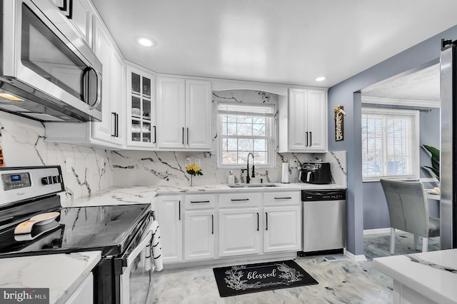 kitchen featuring stainless steel appliances, a sink, glass insert cabinets, and white cabinetry