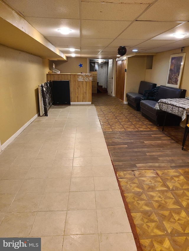 interior space with a paneled ceiling and tile patterned floors