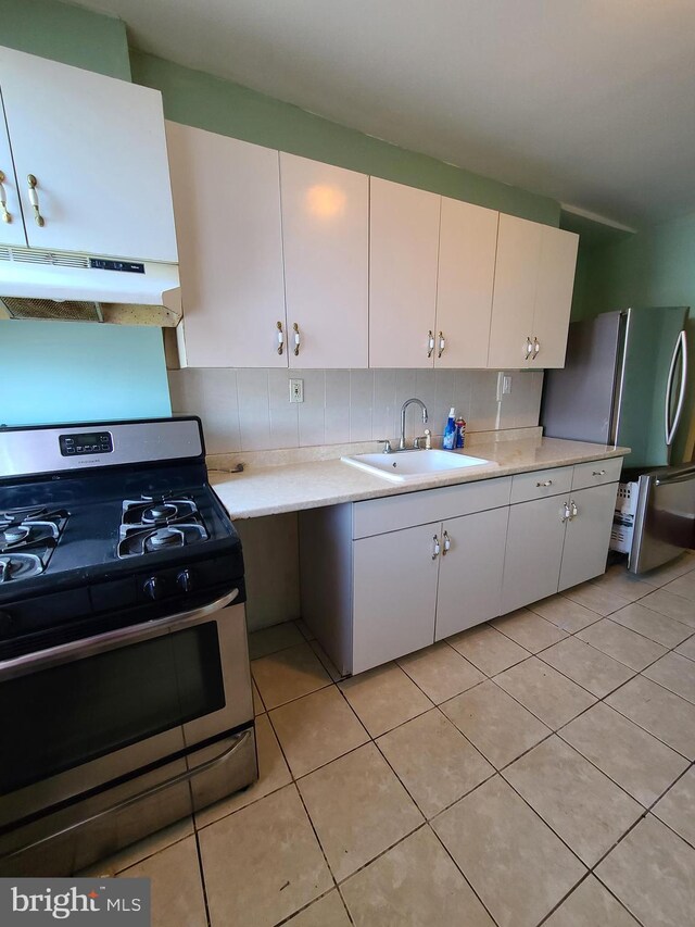 kitchen with sink, white cabinetry, stainless steel appliances, light tile patterned flooring, and decorative backsplash