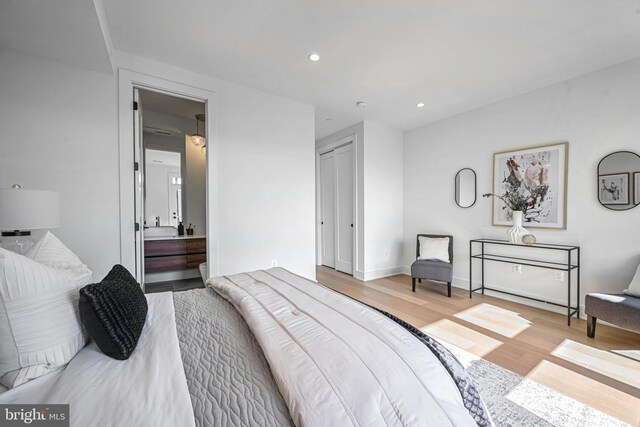 bedroom with light wood-type flooring and ensuite bath