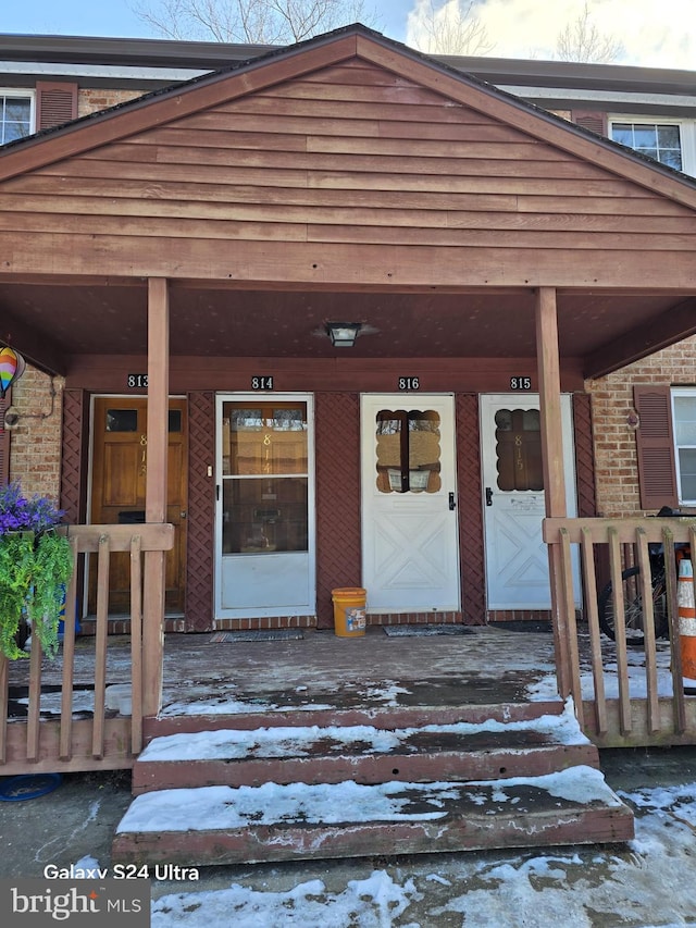 snow covered property entrance with covered porch