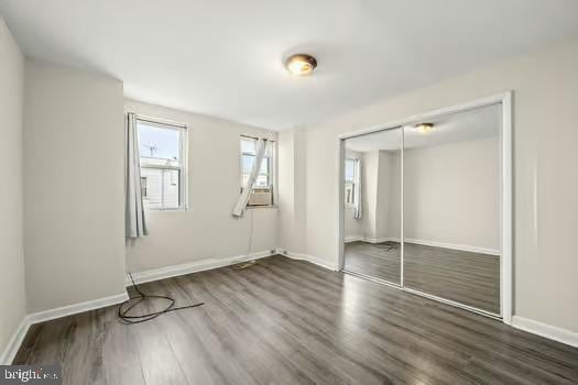 unfurnished bedroom featuring dark wood-type flooring and a closet