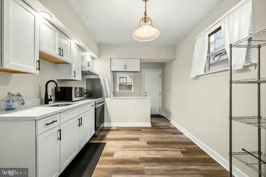 kitchen featuring stainless steel range with electric stovetop, sink, wood-type flooring, and white cabinets