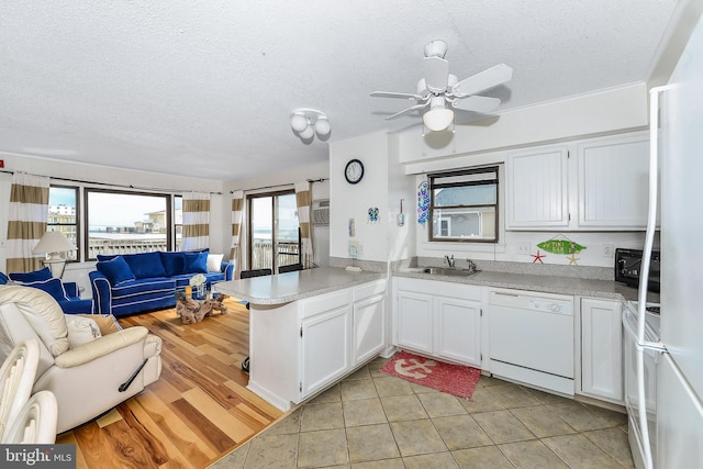 kitchen featuring sink, white cabinets, white appliances, kitchen peninsula, and a textured ceiling