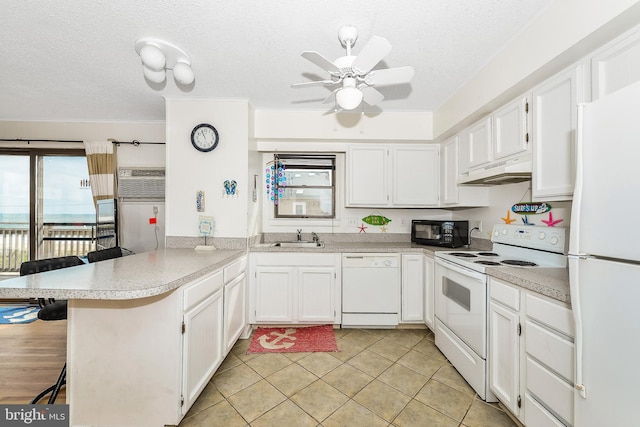 kitchen with white cabinetry, a breakfast bar, white appliances, and kitchen peninsula