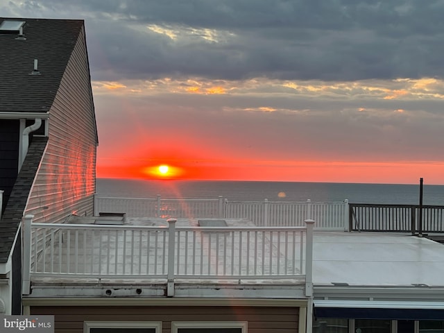 deck at dusk featuring a water view