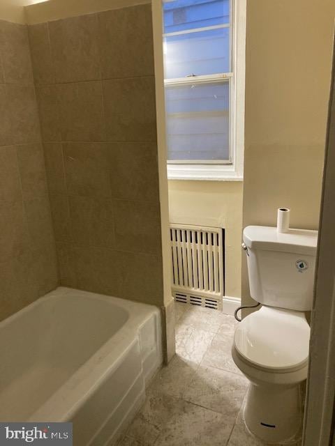 bathroom featuring tile patterned flooring, a bath, radiator heating unit, and toilet