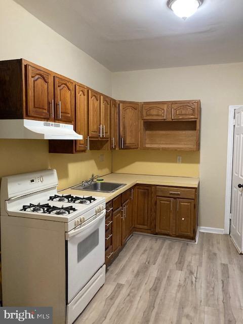 kitchen with sink, light hardwood / wood-style flooring, and gas range gas stove