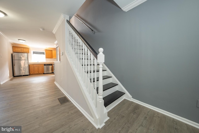 stairway with crown molding, wood-type flooring, and sink