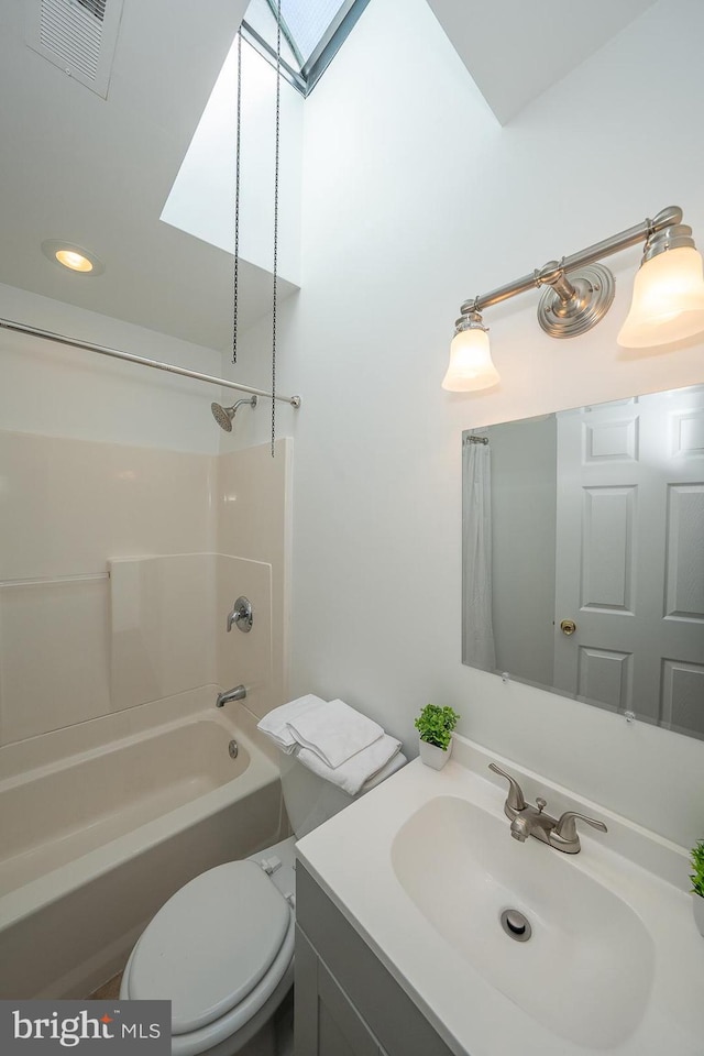 full bathroom with a skylight, toilet, vanity, and shower / bathing tub combination