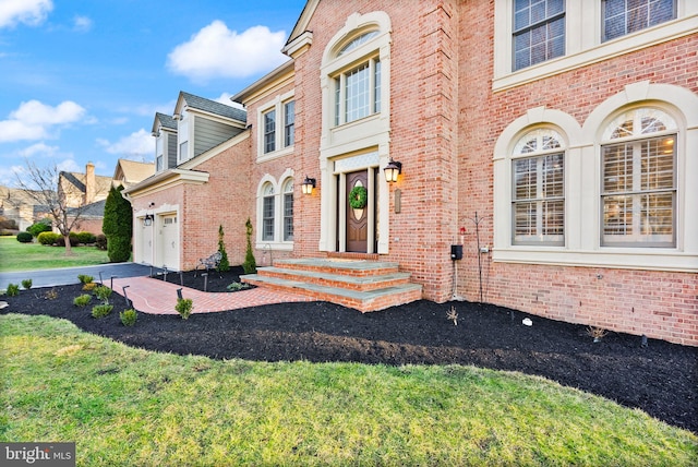 view of exterior entry featuring a garage and a lawn