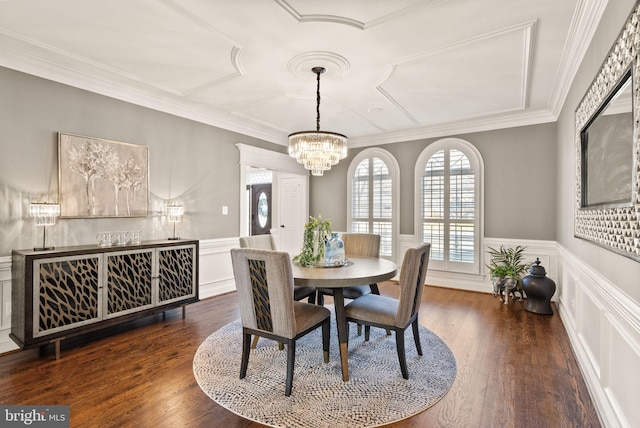 dining area with dark wood-type flooring, ornamental molding, and a chandelier