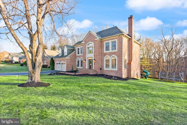 front facade featuring a garage, a trampoline, and a front lawn