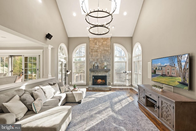 living room with dark hardwood / wood-style floors, high vaulted ceiling, a stone fireplace, and a wealth of natural light