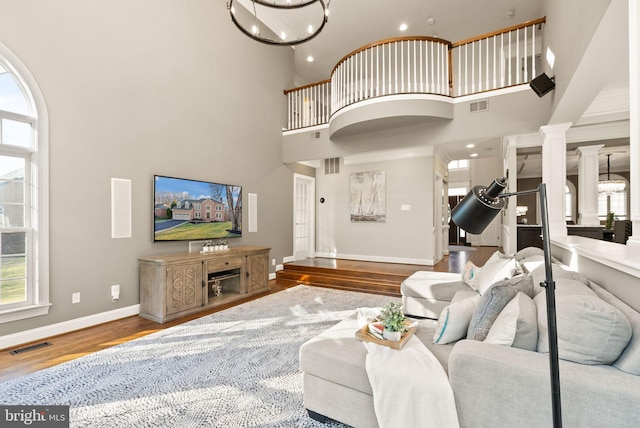 living room with ornate columns, plenty of natural light, a high ceiling, and hardwood / wood-style floors