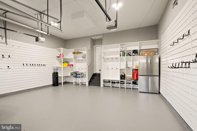 garage with a garage door opener and stainless steel refrigerator