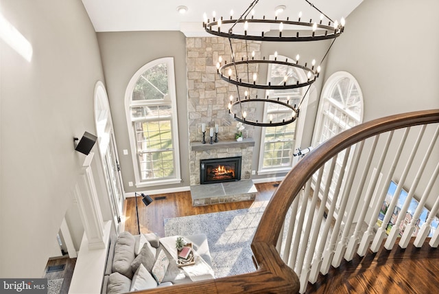 stairs with plenty of natural light, hardwood / wood-style floors, a notable chandelier, and a fireplace