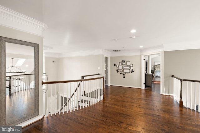 hall featuring an inviting chandelier, dark wood-type flooring, and ornamental molding