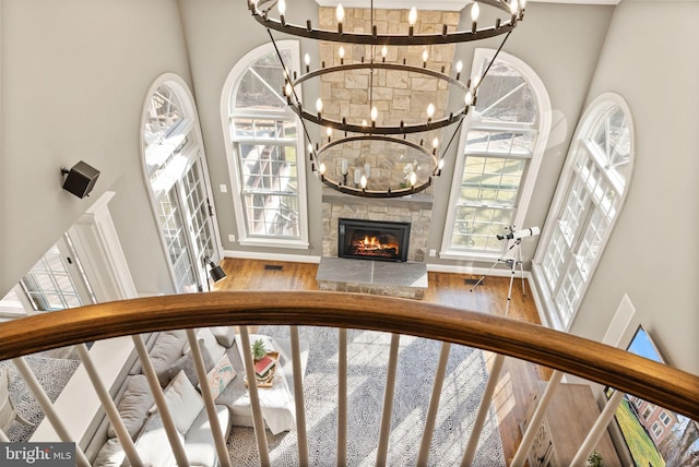 staircase with an inviting chandelier, hardwood / wood-style flooring, a fireplace, and a high ceiling