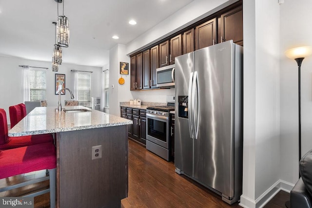 kitchen with appliances with stainless steel finishes, sink, a breakfast bar area, dark brown cabinetry, and a center island with sink