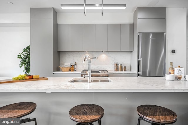 kitchen featuring stainless steel fridge, a kitchen breakfast bar, kitchen peninsula, and gray cabinetry