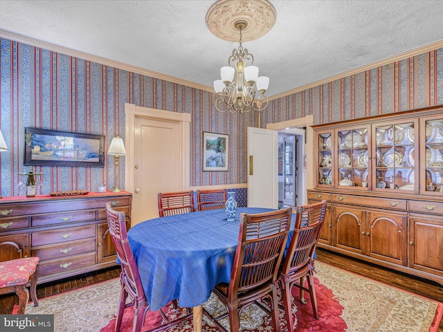 dining area with an inviting chandelier, ornamental molding, hardwood / wood-style floors, and a textured ceiling