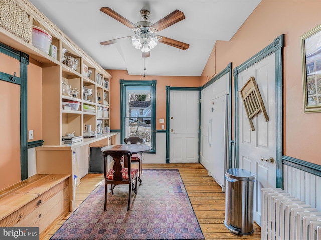 home office featuring light hardwood / wood-style flooring, radiator heating unit, and ceiling fan