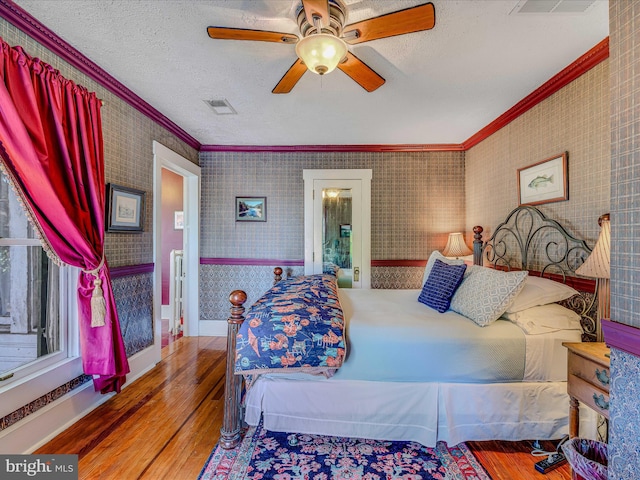 bedroom featuring ornamental molding, hardwood / wood-style floors, and a textured ceiling