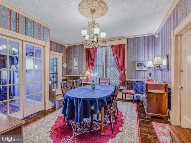 dining room with crown molding, dark hardwood / wood-style flooring, a chandelier, and a textured ceiling