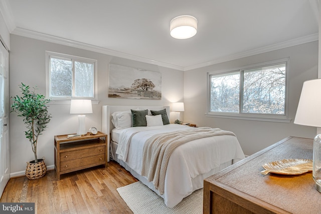 bedroom featuring multiple windows, crown molding, and light wood-type flooring