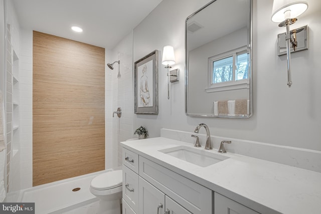 bathroom with vanity, tiled shower, and toilet