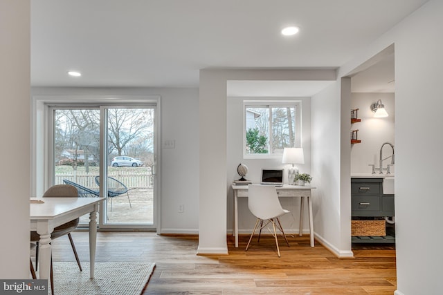 home office featuring sink, light hardwood / wood-style flooring, and a wealth of natural light