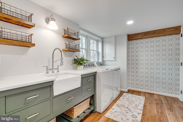 washroom with sink, cabinets, independent washer and dryer, and light wood-type flooring