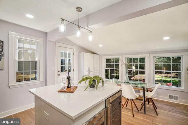 kitchen featuring a kitchen island, pendant lighting, white cabinets, wine cooler, and light hardwood / wood-style flooring