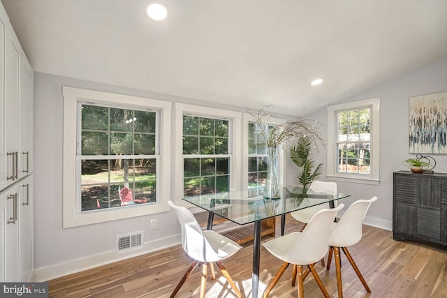 dining space featuring lofted ceiling and light hardwood / wood-style flooring