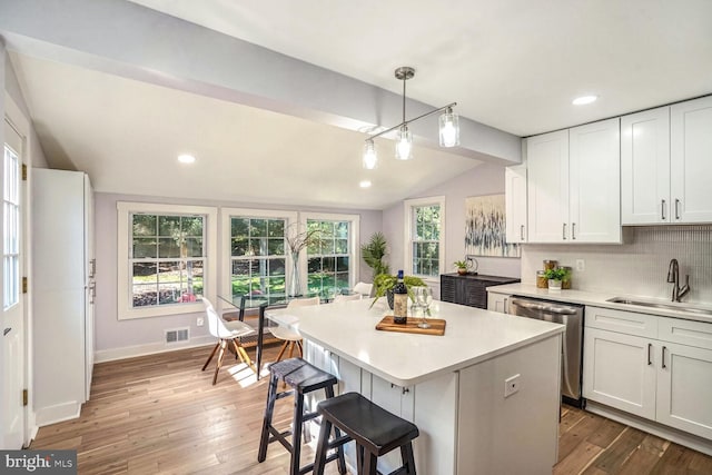 kitchen with sink, decorative light fixtures, lofted ceiling with beams, dishwasher, and white cabinets