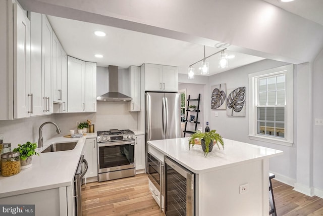 kitchen featuring appliances with stainless steel finishes, decorative light fixtures, wine cooler, a center island, and wall chimney exhaust hood