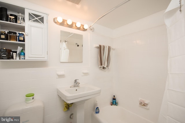 bathroom featuring tile walls, shower / tub combo, and toilet