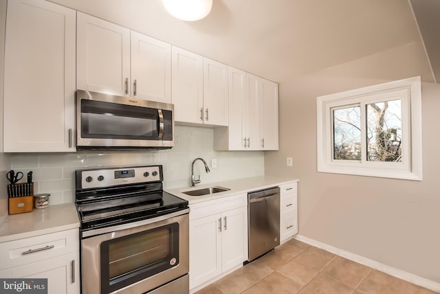 kitchen featuring sink, light tile patterned floors, backsplash, stainless steel appliances, and white cabinets