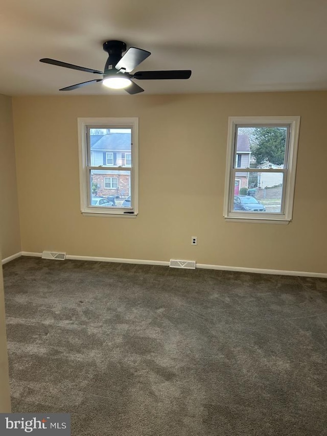 empty room with dark colored carpet and ceiling fan