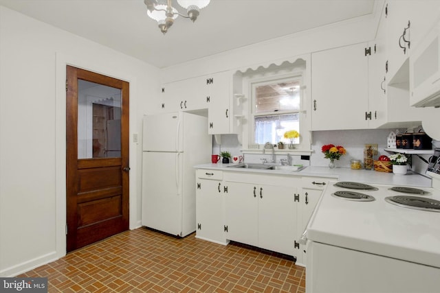 kitchen with white fridge, sink, white cabinets, and a chandelier