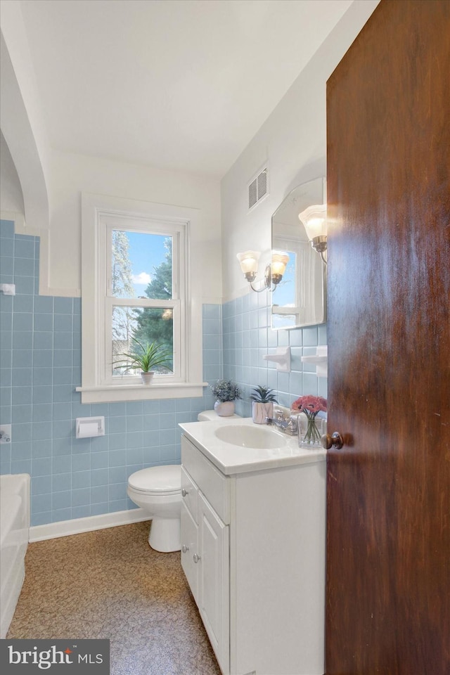 bathroom with vanity, tile walls, and toilet