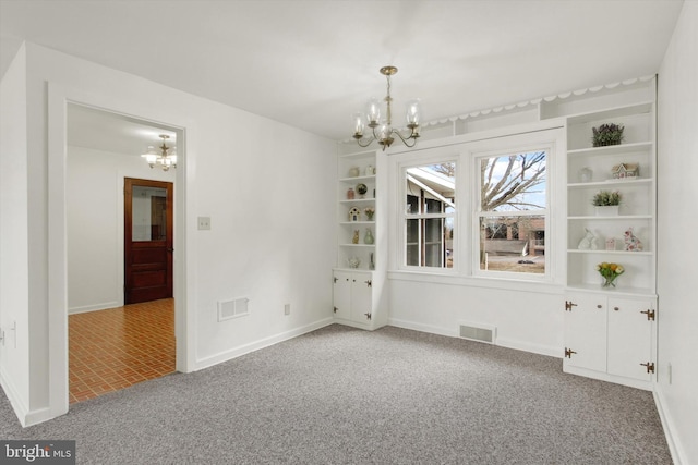 carpeted spare room featuring a chandelier