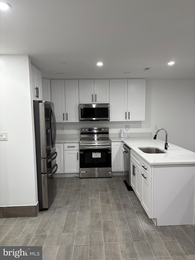 kitchen featuring sink, kitchen peninsula, white cabinets, and appliances with stainless steel finishes