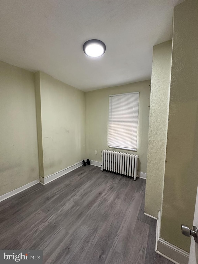 laundry area featuring radiator heating unit and wood-type flooring