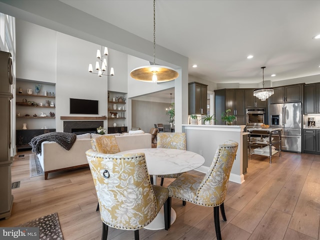 dining room featuring a notable chandelier, recessed lighting, a fireplace, and light wood-type flooring